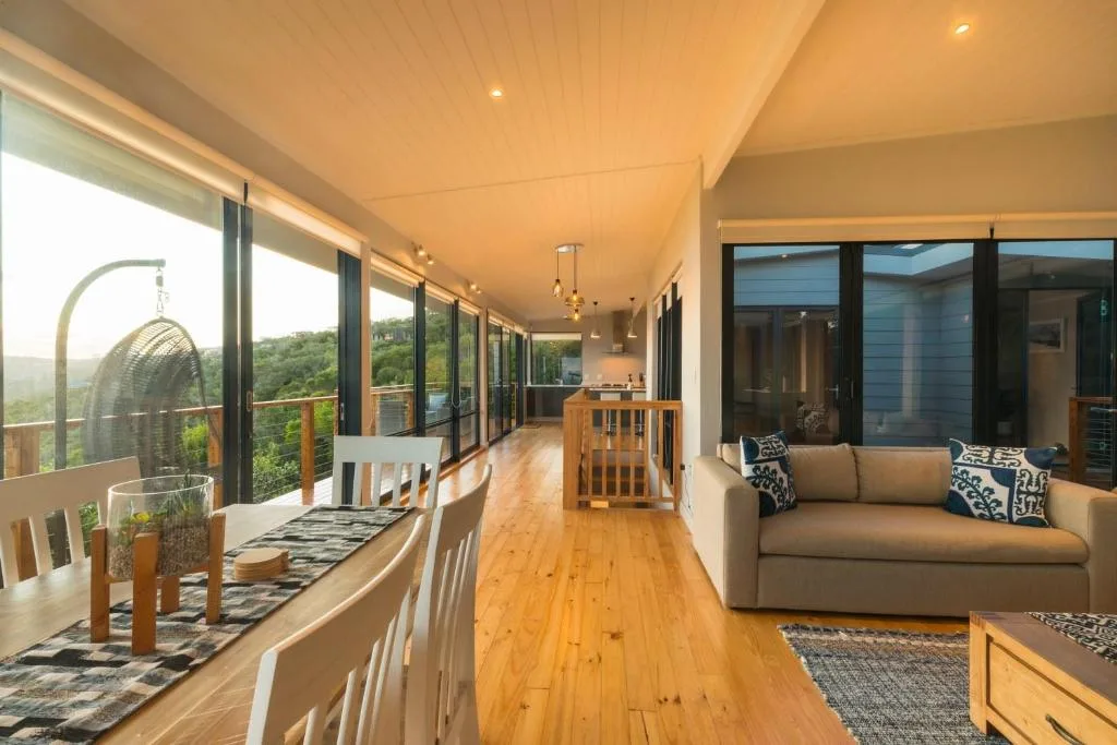 Spacious covered deck with lounge seating and forest views overlooking Garden Route