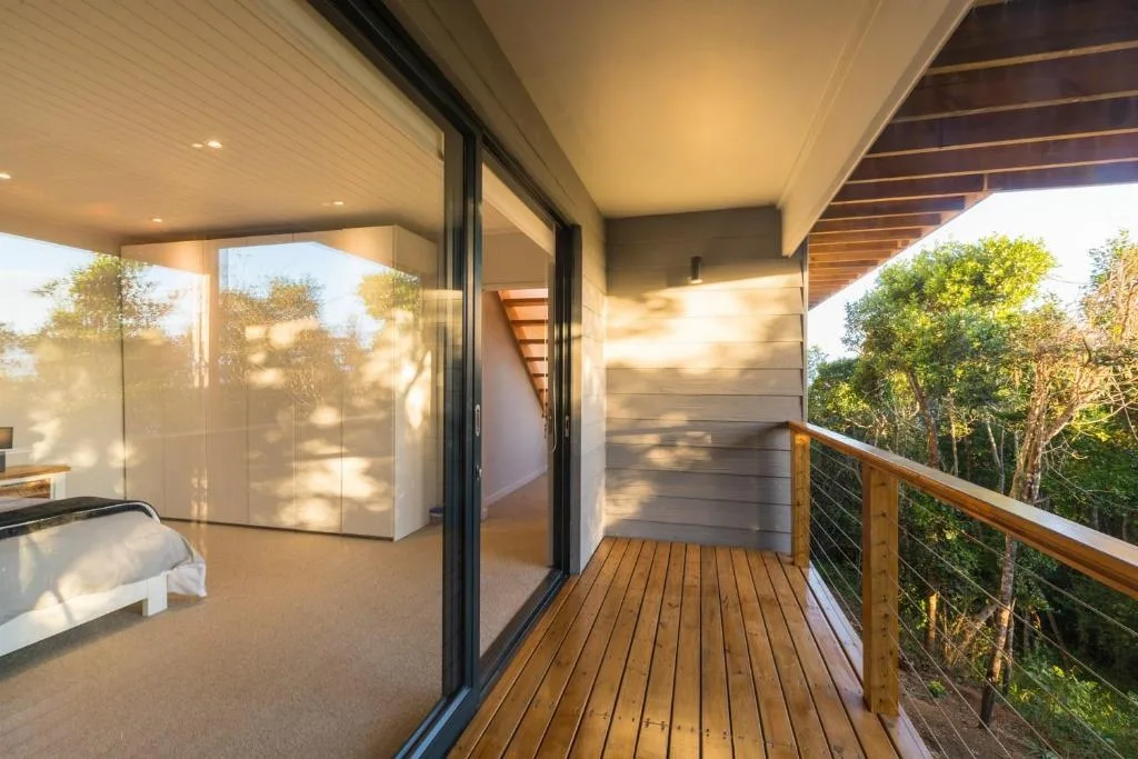Modern wooden deck with cable railing overlooking forest vegetation