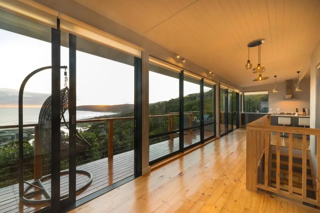 Spacious wooden deck with lagoon views, modern railing, hanging chair