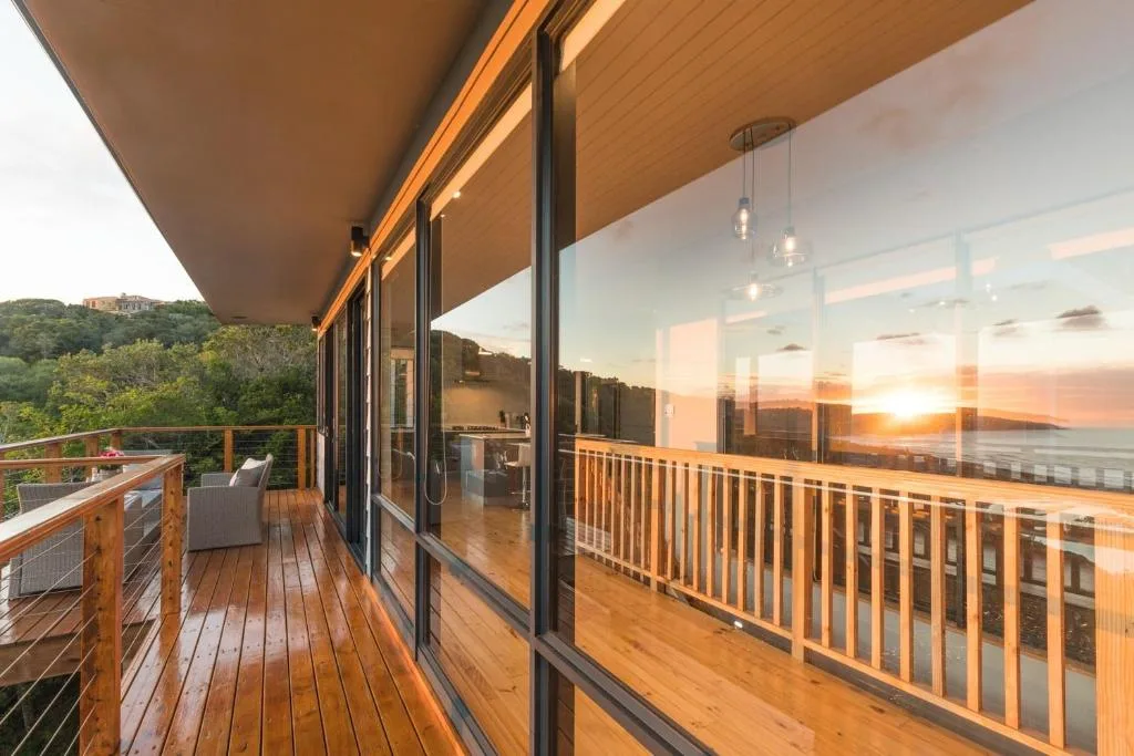 Wooden deck with ocean view at sunset, cable railing, outdoor seating