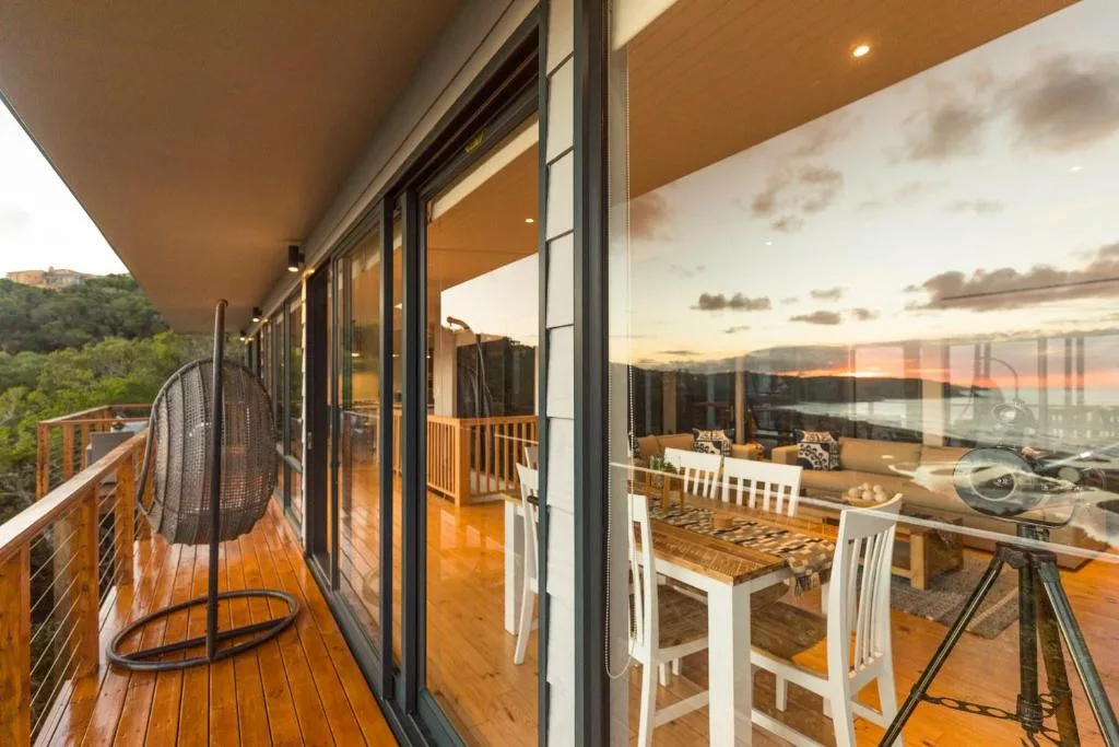 Wooden deck with hanging chair overlooking scenic landscape at sunset