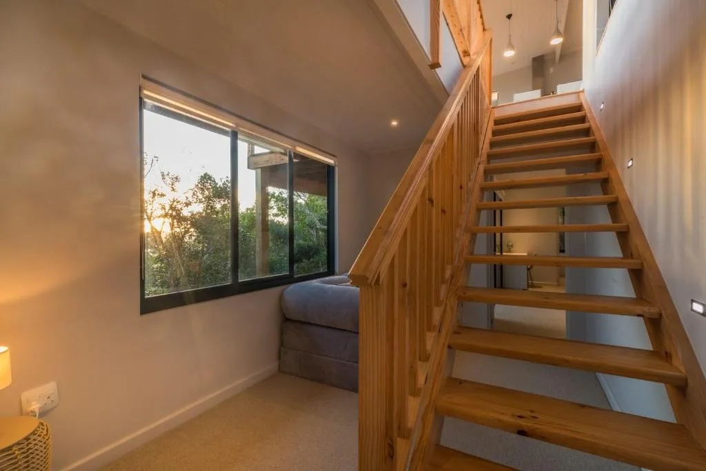 Modern wooden staircase with built-in window seating overlooking trees