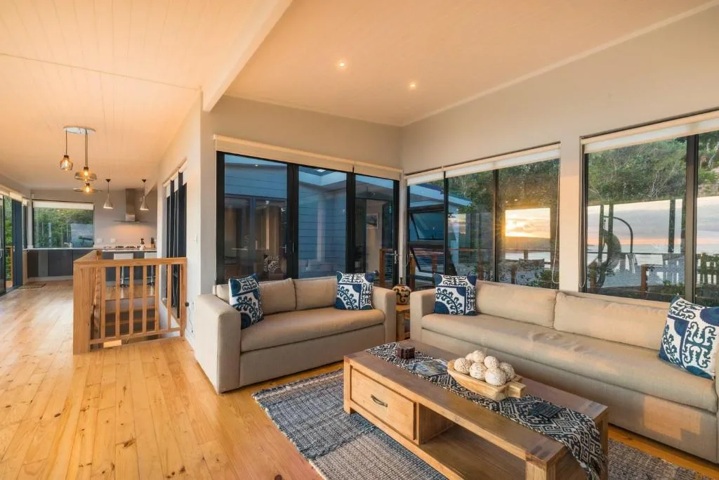 Modern living room with neutral sofas, wooden coffee table, and large windows overlooking garden