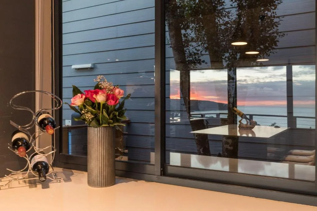 Sunset over water visible through expansive windows from interior