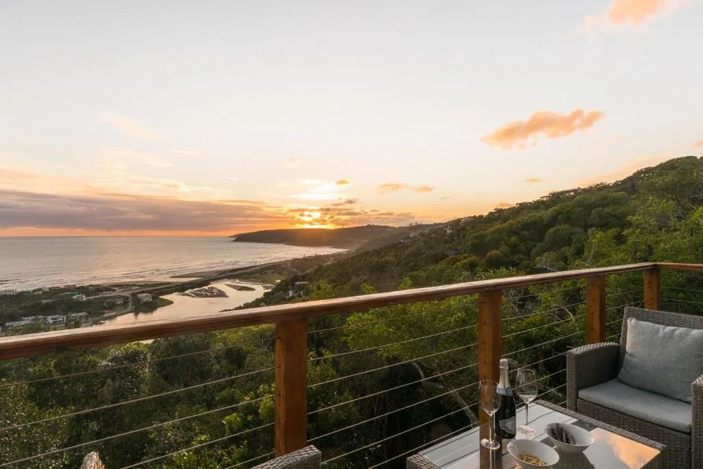 Sunset vista over coastal lagoon and forested hillside from deck