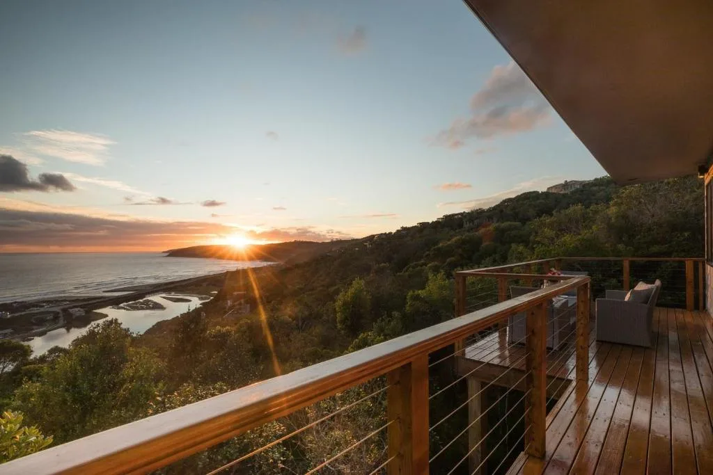 Sunset over ocean and lagoon from elevated wooden deck with railing