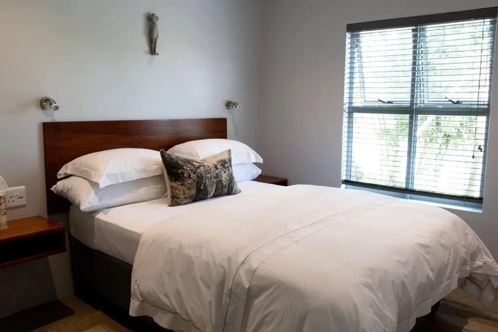 Bright bedroom with queen bed, white linens, wooden headboard, large window