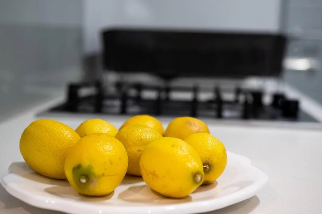 Fresh yellow lemons arranged on white plate in modern kitchen