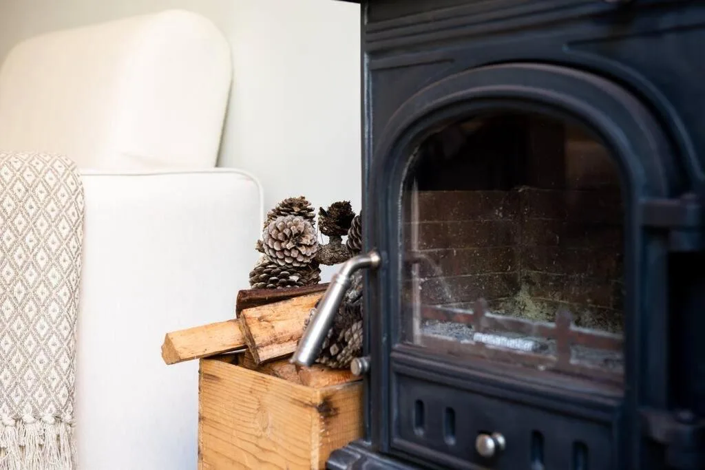 Cozy fireplace detail with decorative pinecones and white cushioned seating nearby