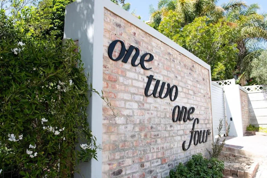 Brick building entrance with property name signage and lush garden surroundings