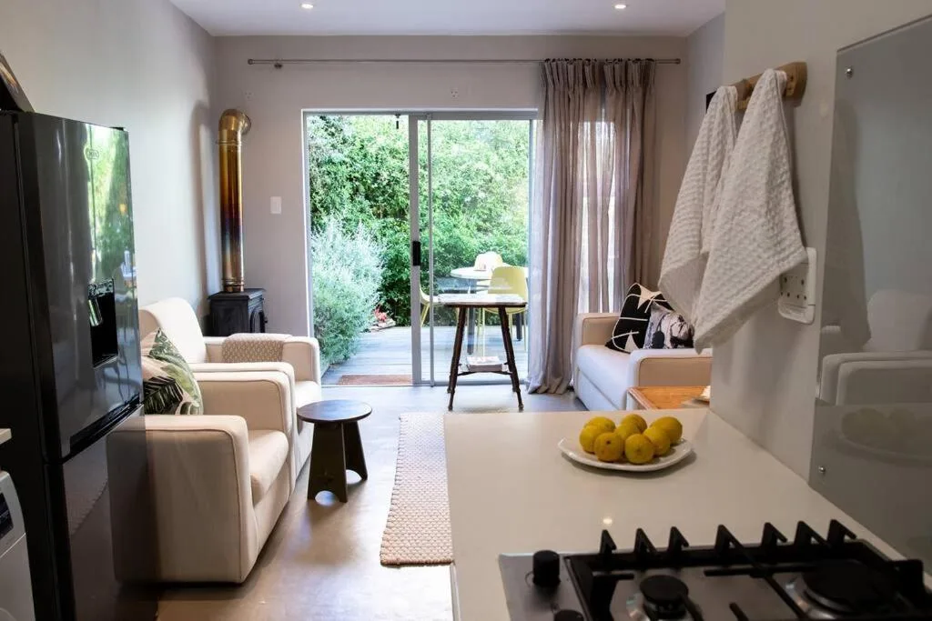 Modern lounge with cream armchairs, TV, and sliding glass doors opening to deck