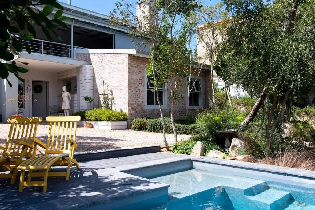 Swimming pool with sun loungers and modern brick house backdrop