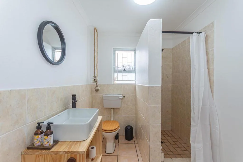 Modern bathroom with vessel sink, toilet, shower cubicle and round mirror