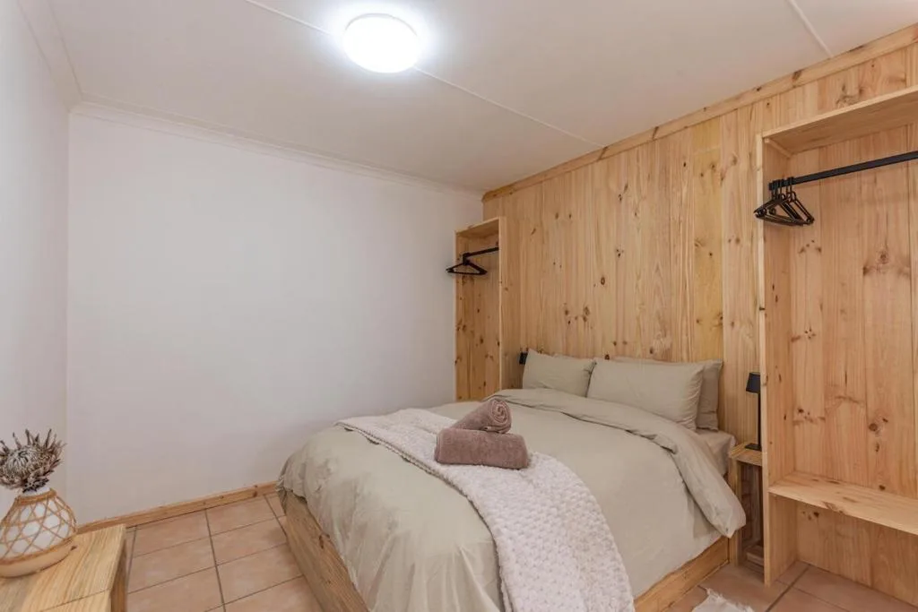 Cozy bedroom with wooden paneling, double bed, cream bedding, and built-in wardrobe