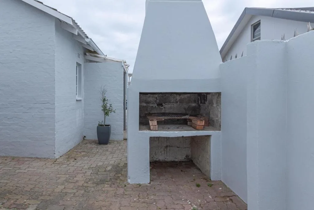 Outdoor braai area with built-in brick grill and white-washed walls