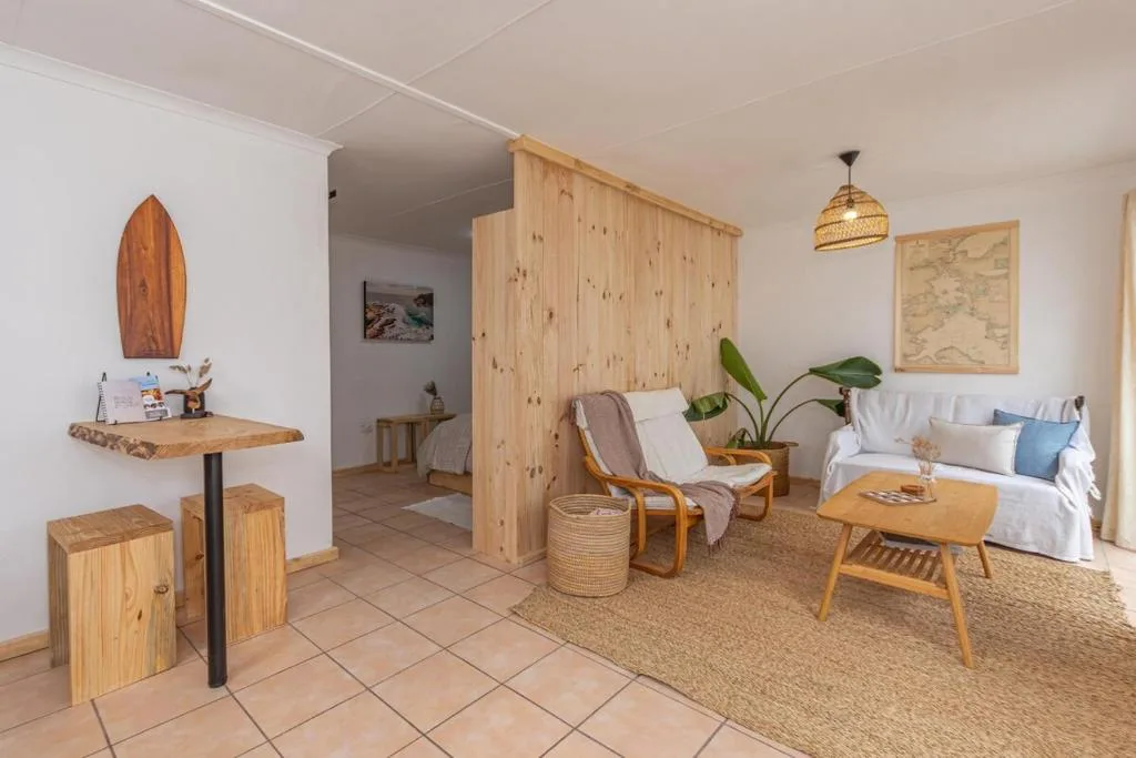 Open-plan lounge with sofa, wooden room divider, and coastal decor