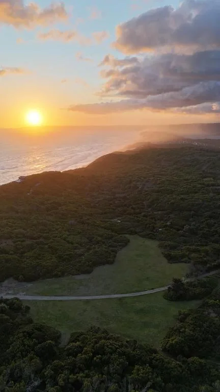 Sunset over lagoon and ocean with forested cliffs surrounding