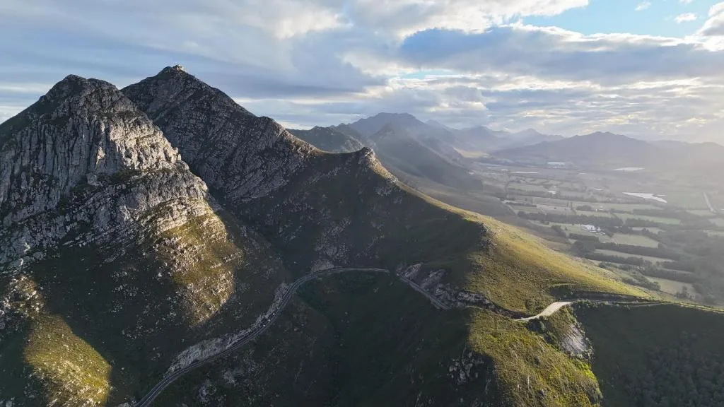 Dramatic mountain peaks overlooking fertile valley and distant farmland