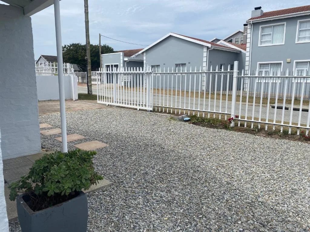 White-fenced driveway and entrance to coastal property with gravel parking area