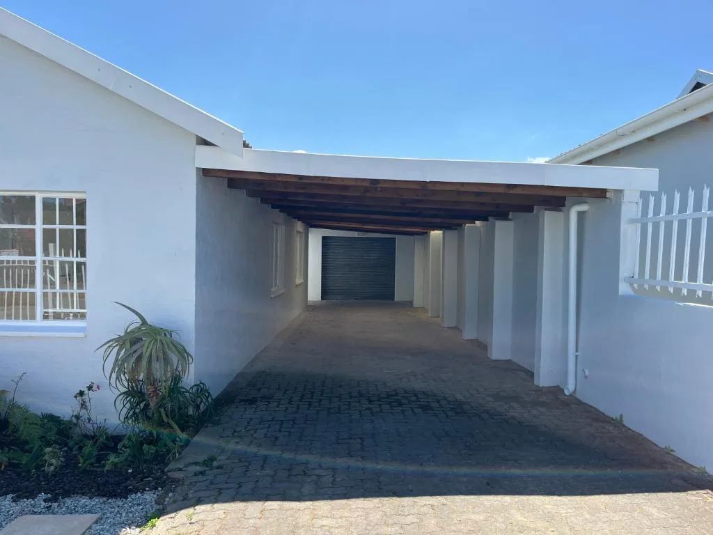 White modern house with covered carport and dark garage door entrance