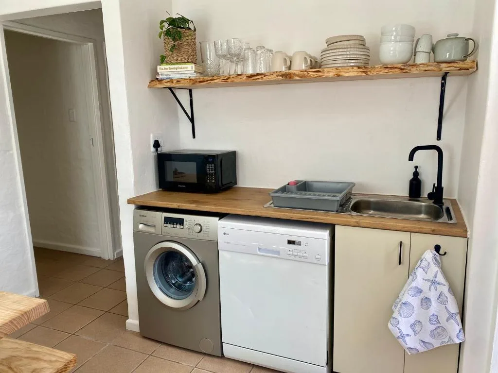 Modern kitchenette with washing machine, dishwasher, sink, and open shelving