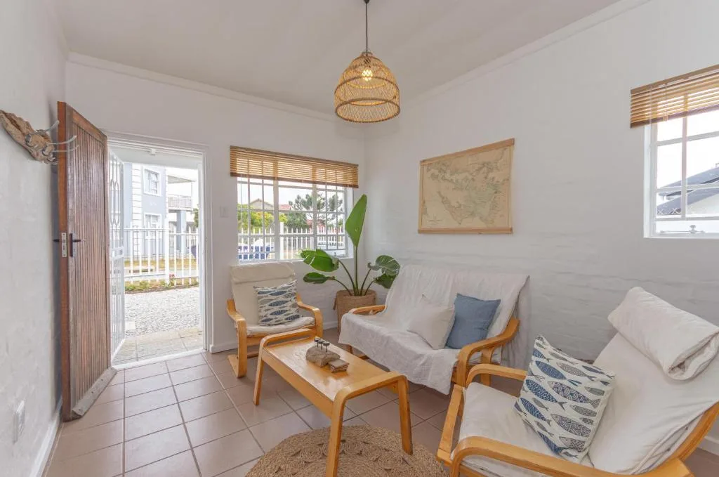 Bright lounge with wooden chairs, sofa, pendant light, and garden view