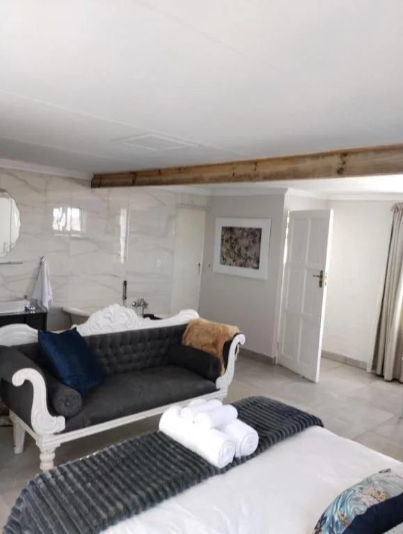 Spacious bedroom with bed, elegant sofa, and exposed wooden beam ceiling