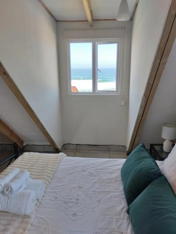 Bedroom with ocean view through double doors and coastal landscape