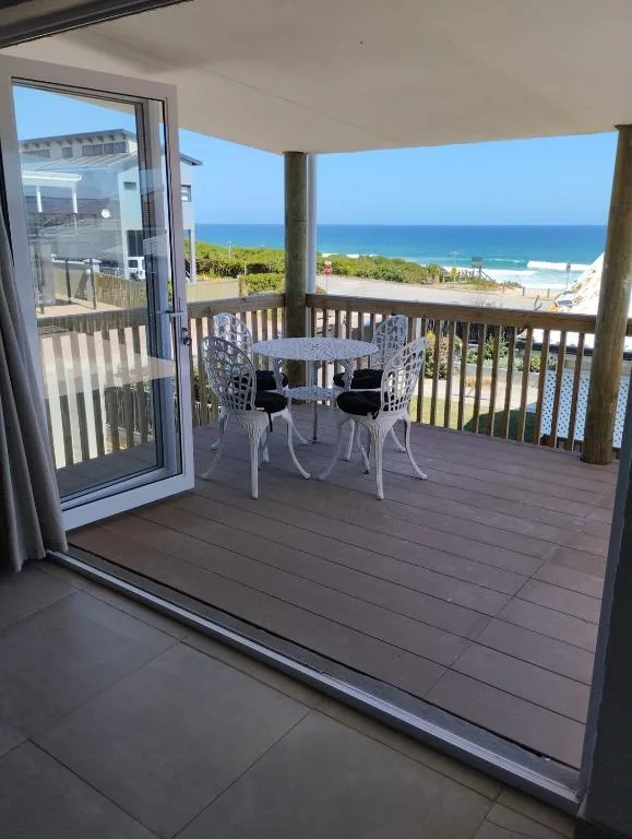 Wooden deck with dining table overlooking ocean and beach views