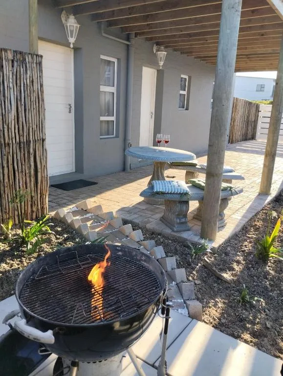 Covered patio with lit braai grill, seating bench, and garden views