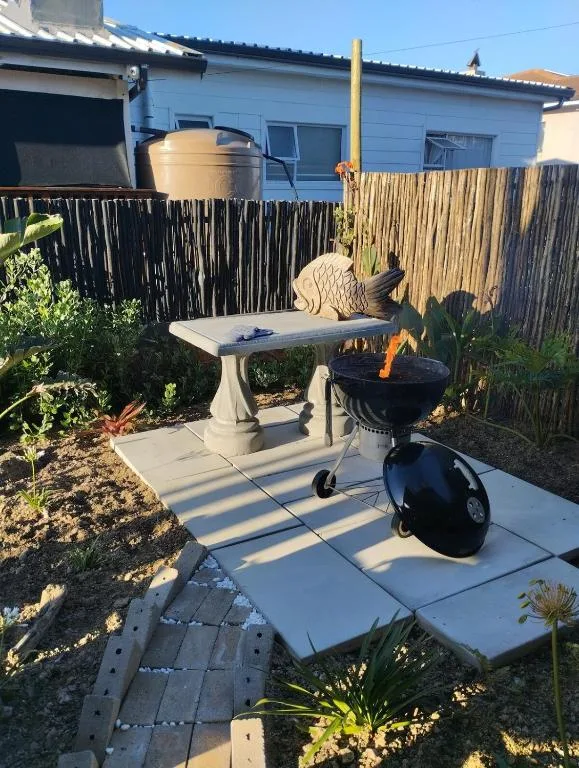 Outdoor braai area with grill and seating table in cottage garden