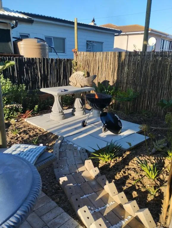 Outdoor patio area with round table, chairs, and surrounding garden landscaping