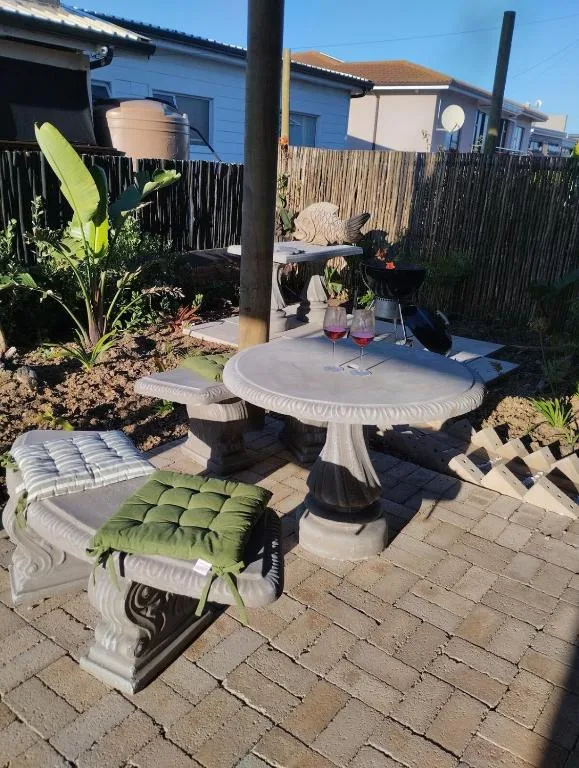 Outdoor patio area with round table, seating, and tropical plants