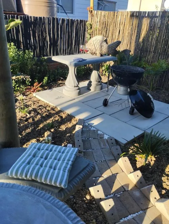 Outdoor patio with table, braai grill, and striped cushioned seating