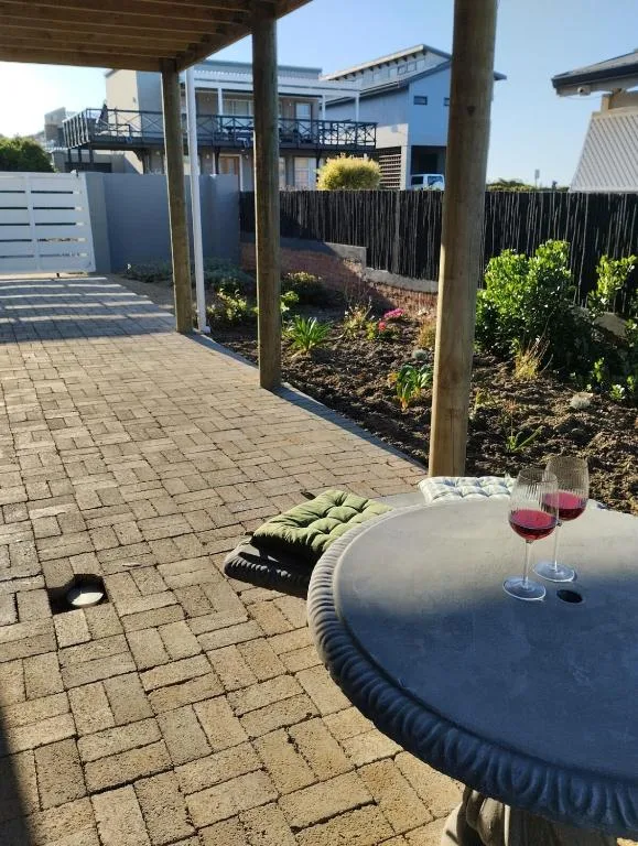 Covered patio with cushioned seating and wine glasses overlooking garden