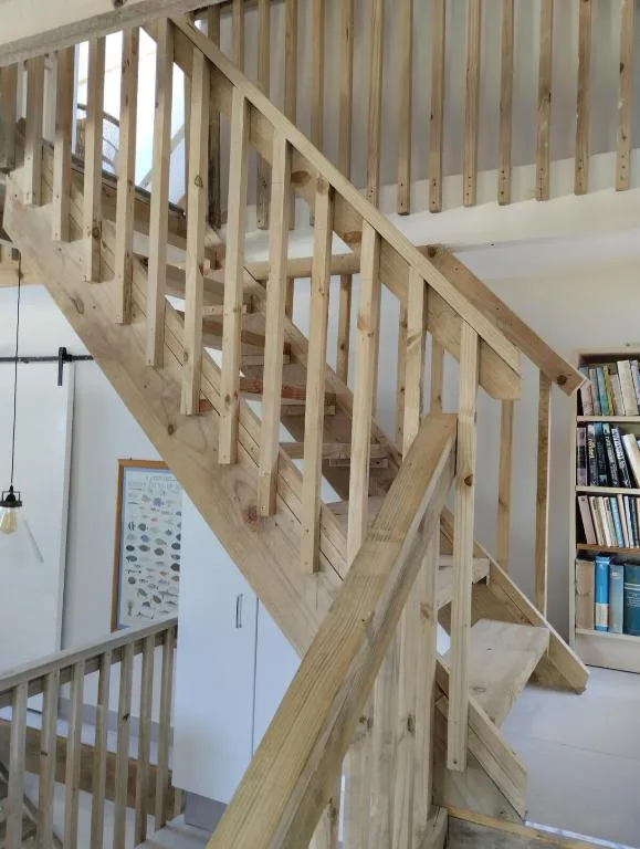 Modern wooden staircase with geometric railings in open-plan interior space