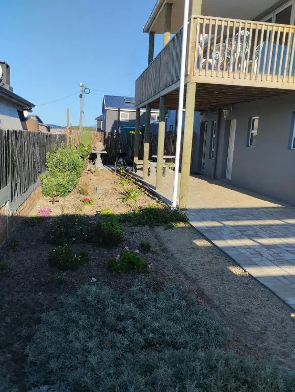 Modern beachfront cottage with yellow deck, landscaped garden, and neighboring properties