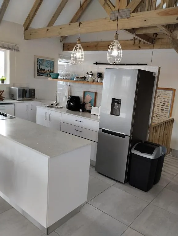 Modern kitchen with white cabinetry, stainless steel fridge, and exposed wooden beams