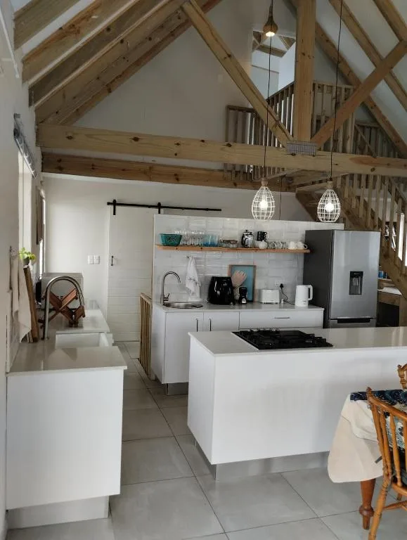 Modern kitchen with white cabinetry, stainless steel appliances, and exposed wooden beams
