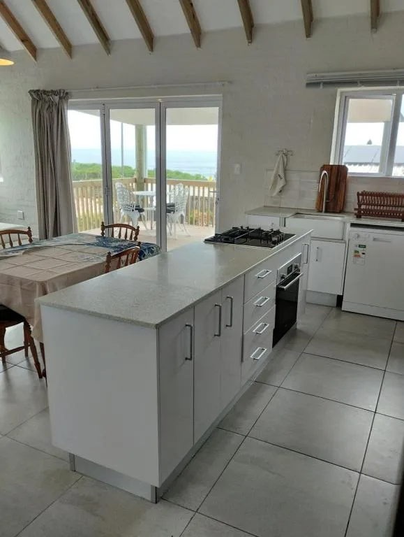 Modern kitchen with island, stove, and ocean views through glass doors