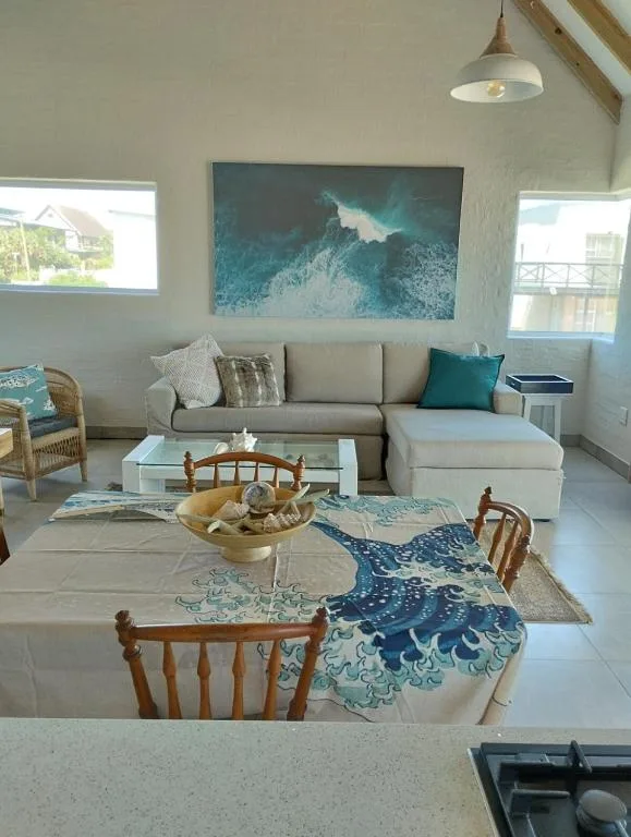 Bright open-plan lounge with grey sectional sofa and ocean artwork