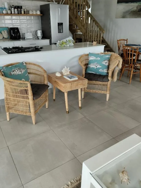 Open-plan lounge with wicker armchairs and kitchen visible beyond