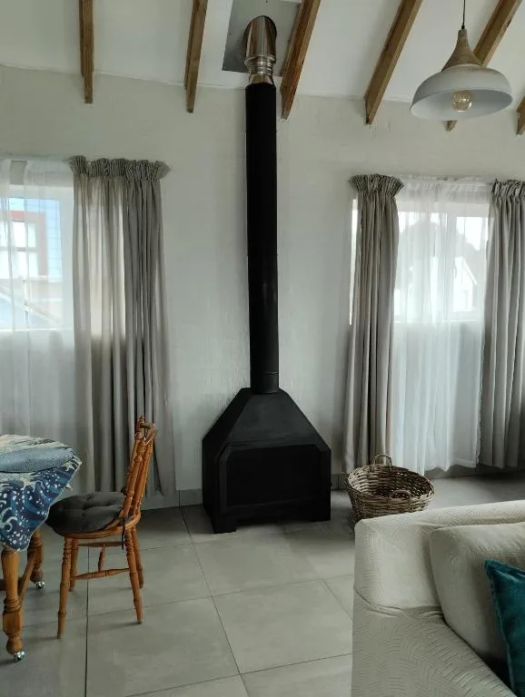 Spacious lounge with wood beams, fireplace, and large windows with curtains