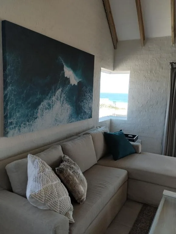 Coastal lounge with beige sofa, ocean artwork, and beach view window
