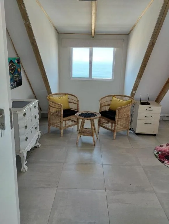 Bright loft lounge with two wicker chairs, ocean view window, and modern furnishings