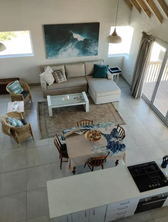 Bright open-plan lounge with beige sofa, ocean artwork, and natural light from windows