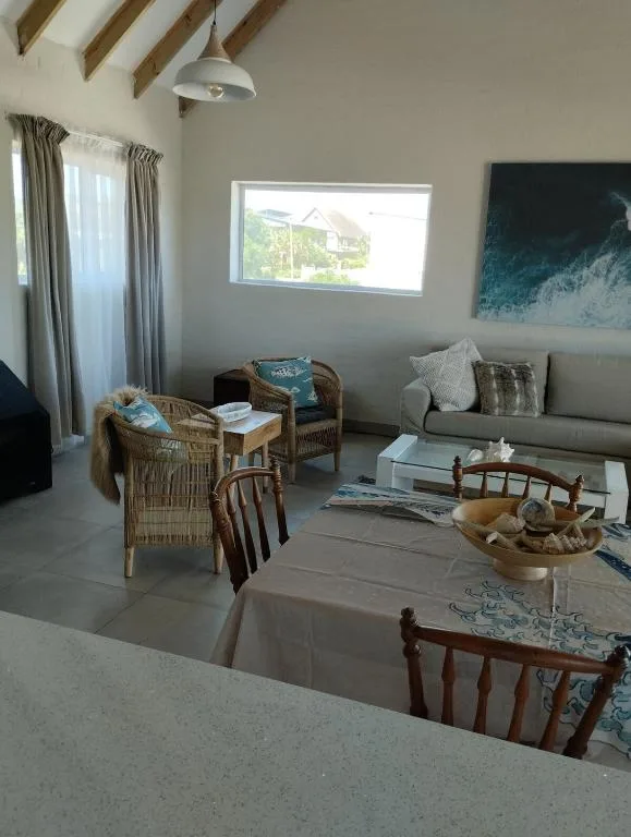 Open-plan lounge with wicker chairs, gray sofa, and window views