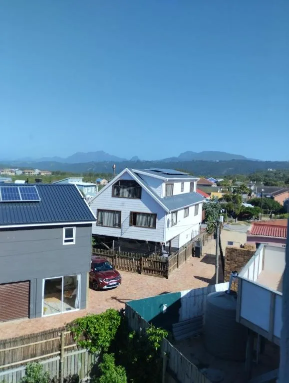 White holiday home with mountain backdrop under clear blue sky