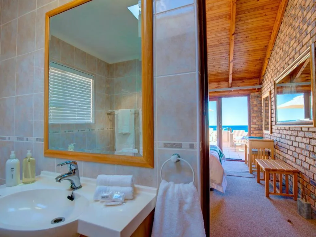 Bright bathroom with vanity sink, large mirror, and ocean view beyond