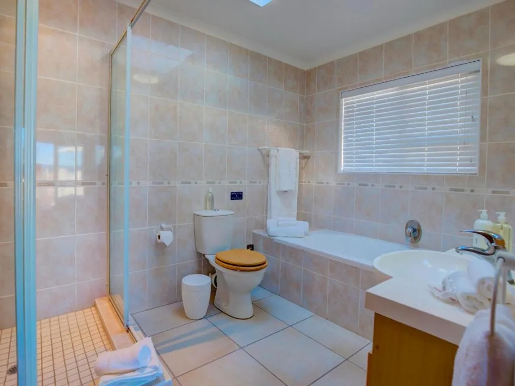 Spacious bathroom with walk-in shower, bathtub, double vanity, and natural light